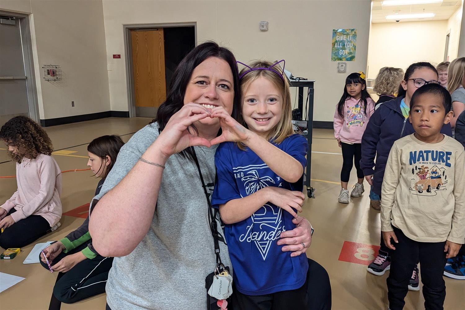 Stolley Park Principal, Whitney Flower, smiling with a student and holding the "heart" symbol together with their hands.
